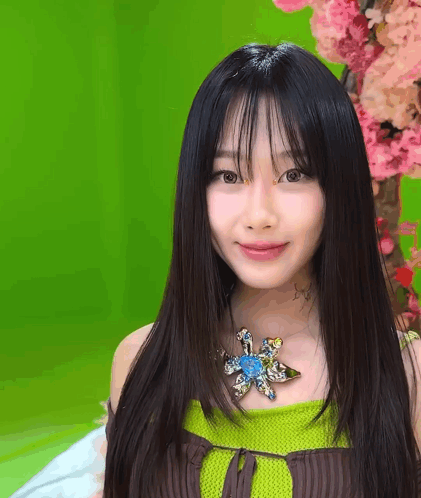 A Woman With Long Black Hair And A Flower Necklace GIF