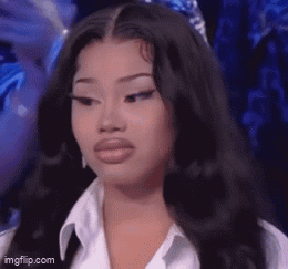 A Woman With Long Black Hair And A White Shirt Is Looking At The Camera . GIF