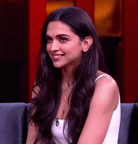 A Woman With Long Black Hair And A White Top Smiles GIF