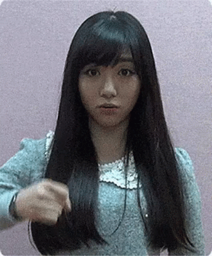 A Woman With Long Black Hair And Bangs Is Holding Her Hair In Her Hand . GIF