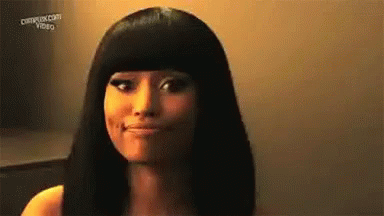 A Woman With Long Black Hair And Bangs Is Smiling And Looking At The Camera . GIF