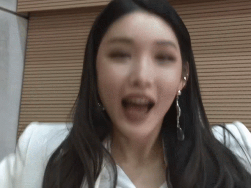 A Woman With Long Black Hair And Earrings Is Making A Funny Face GIF