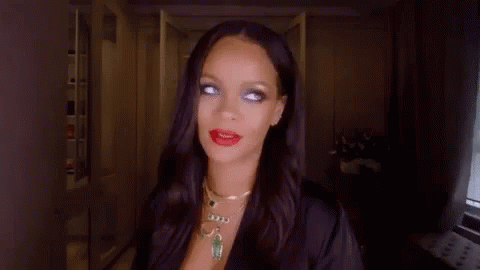 A Woman With Long Black Hair And Red Lipstick Is Wearing A Black Robe And Necklace . GIF