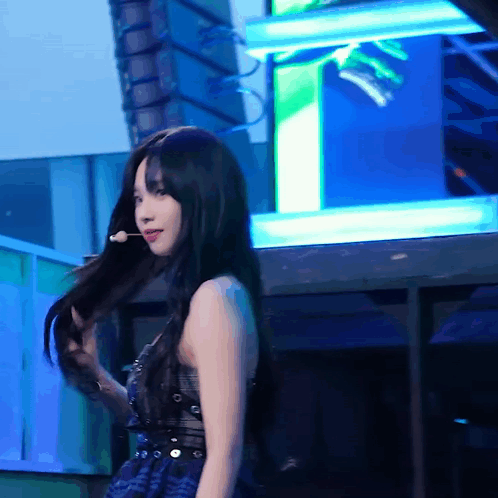 A Woman With Long Black Hair Is Holding A Microphone GIF