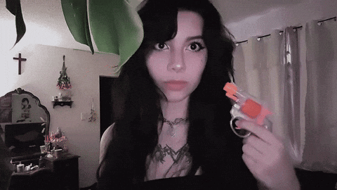 A Woman With Long Black Hair Is Holding A Small Toy Gun GIF