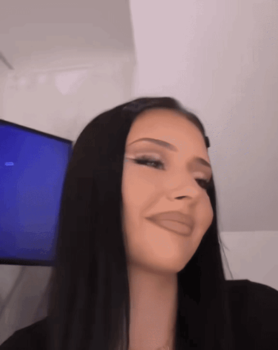 A Woman With Long Black Hair Is Making A Funny Face In Front Of A Television GIF