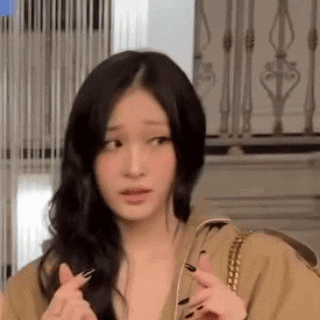 a woman with long black hair is making a funny face while holding her fingers together .