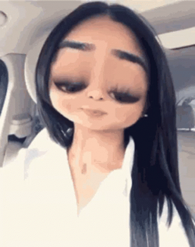 A Woman With Long Black Hair Is Sitting In A Car With A Cartoon Face . GIF