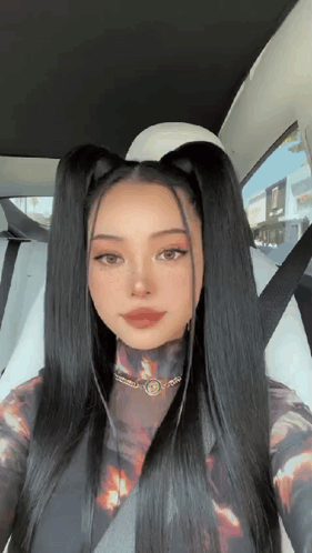 A Woman With Long Black Hair Is Sitting In A Car With A Seat Belt On . GIF