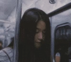 A Woman With Long Black Hair Is Sitting On A Bus With Her Eyes Closed . GIF