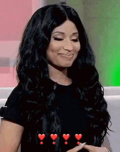A Woman With Long Black Hair Is Sitting On A Couch With Hearts Around Her . GIF