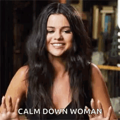 A Woman With Long Black Hair Is Smiling And Giving A Peace Sign . GIF