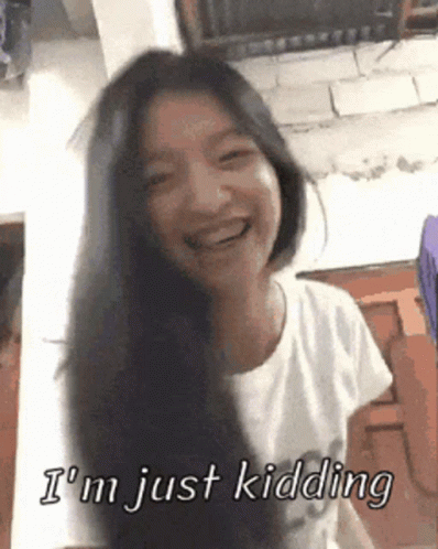 A Woman With Long Black Hair Is Smiling And Says I 'M Just Kidding GIF