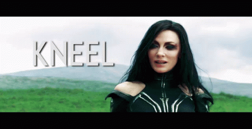 A Woman With Long Black Hair Is Standing In A Field With The Word Kneel Behind Her GIF