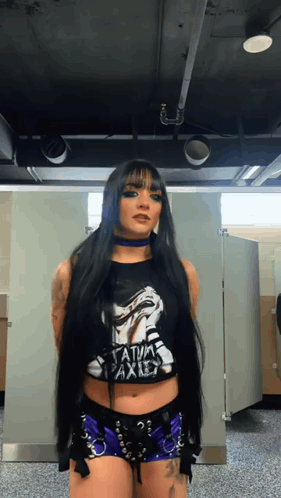 A Woman With Long Black Hair Is Wearing A Black Shirt That Says " Satanic Axis " GIF