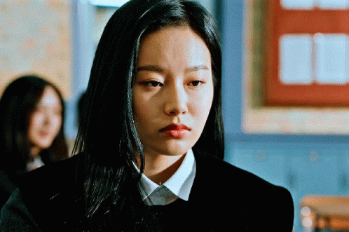A Woman With Long Black Hair Is Wearing A Black Sweater And A White Shirt GIF