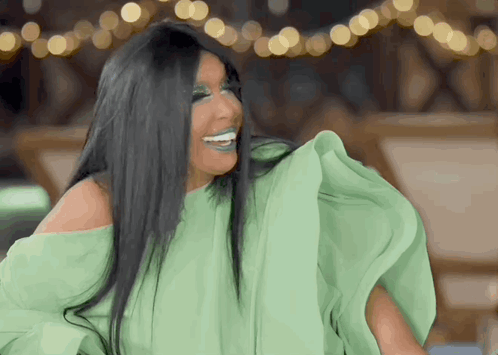 A Woman With Long Black Hair Is Wearing A Green Off The Shoulder Top GIF