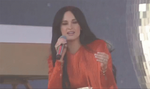 A Woman With Long Black Hair Is Wearing A Red Fringed Dress GIF