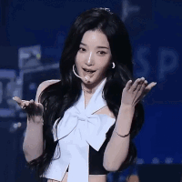A Woman With Long Black Hair Is Wearing A White Bow And A Black Top GIF