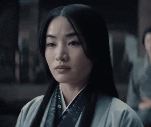 a woman with long black hair is wearing a white jacket