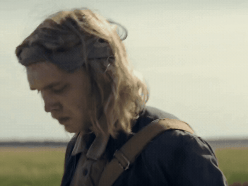 A Woman With Long Blonde Hair And A Brown Backpack Looks Down GIF
