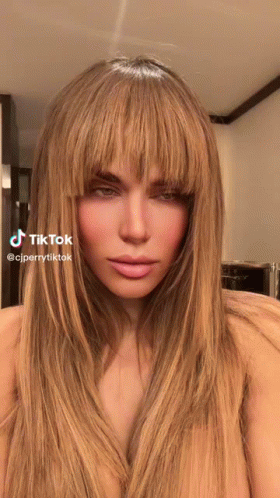 A Woman With Long Blonde Hair And Bangs Has A Tiktok Sticker On Her Face GIF