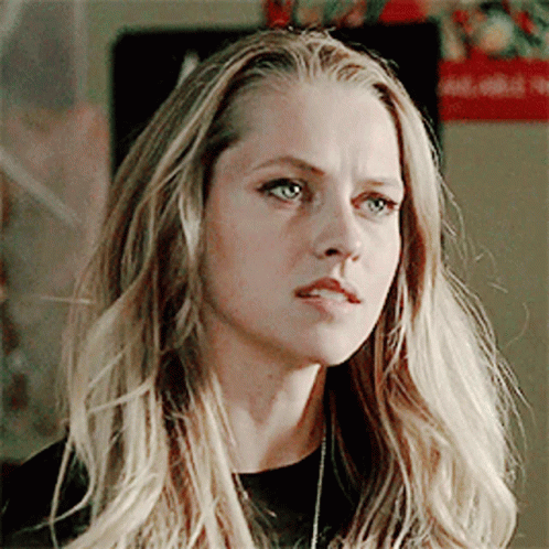 A Woman With Long Blonde Hair And Blue Eyes Is Wearing A Black Shirt GIF