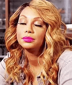 A Woman With Long Blonde Hair And Pink Lipstick Is Making A Funny Face With Her Eyes Closed . GIF