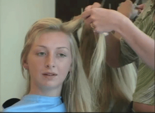 A Woman With Long Blonde Hair Is Getting Her Hair Done GIF