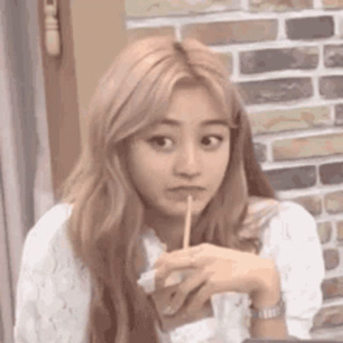 A Woman With Long Blonde Hair Is Holding A Toothpick In Her Mouth . GIF