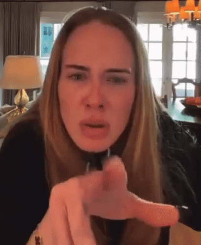 A Woman With Long Blonde Hair Is Pointing At The Camera . GIF