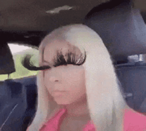 A Woman With Long Blonde Hair Is Sitting In A Car With Her Eyes Closed . GIF