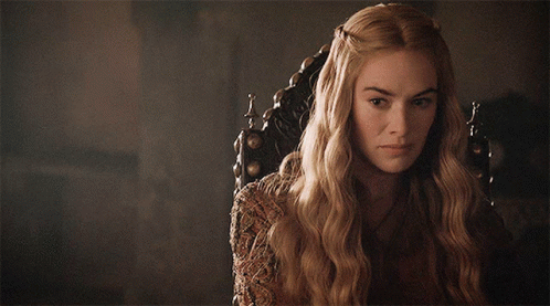 A Woman With Long Blonde Hair Is Sitting In A Chair And Looking At The Camera GIF