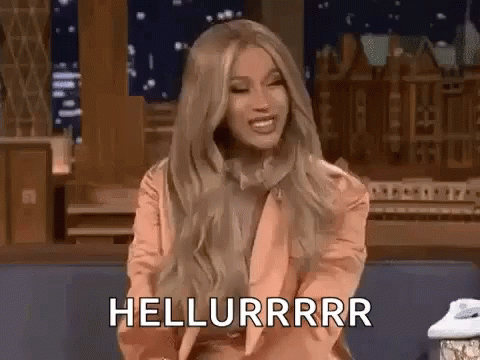 A Woman With Long Blonde Hair Is Sitting On A Couch And Smiling While Talking On A Phone . GIF