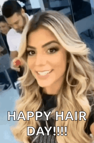 A Woman With Long Blonde Hair Is Smiling And Looking At The Camera With The Words `` Happy Hair Day ! '' GIF