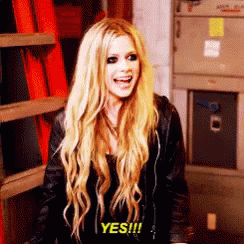 A Woman With Long Blonde Hair Is Smiling And Saying Yes . GIF