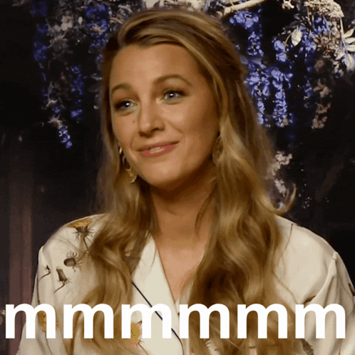 A Woman With Long Blonde Hair Is Smiling And Says Mmmm GIF