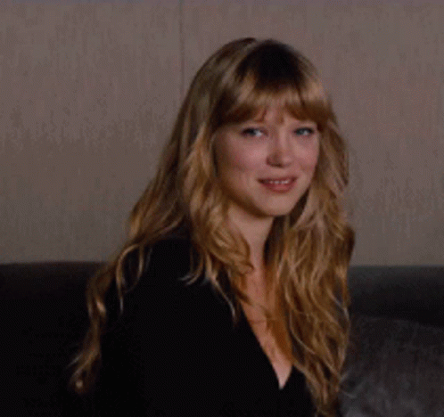 A Woman With Long Blonde Hair Is Smiling While Wearing A Black Top GIF