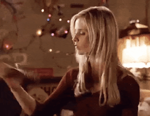 a woman with long blonde hair is standing in front of a christmas tree and a lamp .