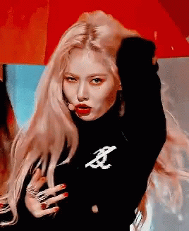 A Woman With Long Blonde Hair Is Wearing A Black Turtleneck Sweater And Red Lipstick . GIF