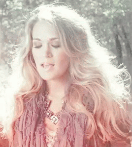 A Woman With Long Blonde Hair Is Wearing A Fringed Jacket And A Necklace GIF
