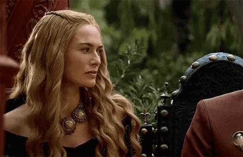 A Woman With Long Blonde Hair Is Wearing A Necklace And Sitting In A Chair . GIF