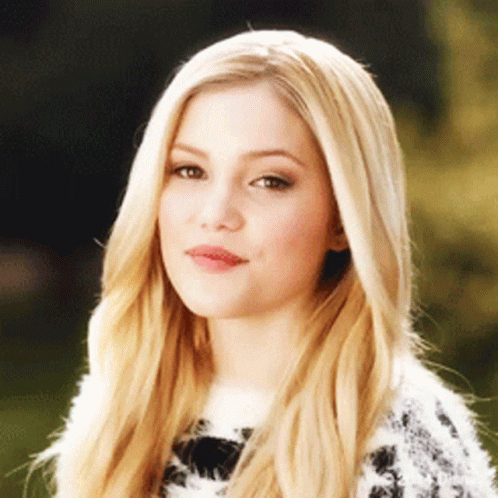 A Woman With Long Blonde Hair Is Wearing A Sweater GIF