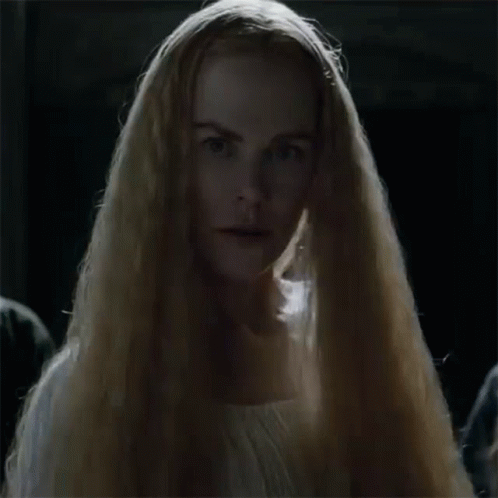 A Woman With Long Blonde Hair Is Wearing A White Dress And A Veil . GIF