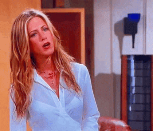 A Woman With Long Blonde Hair Is Wearing A White Shirt And Necklace . GIF
