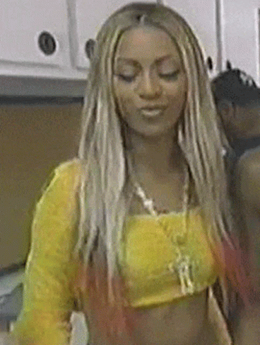 a woman with long blonde hair is wearing a yellow crop top
