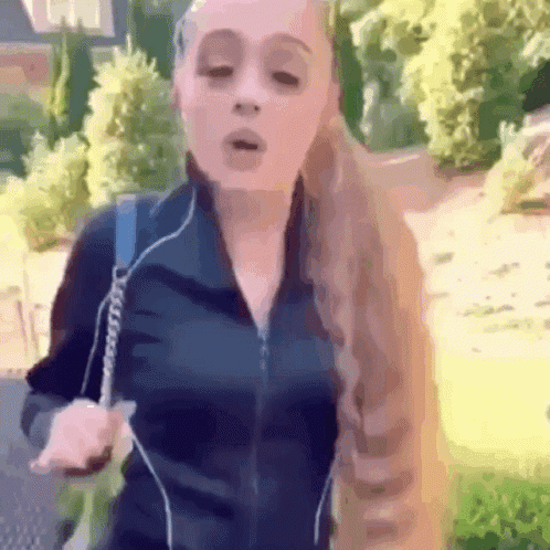 A Woman With Long Blonde Hair Is Wearing Headphones And A Black Jacket GIF