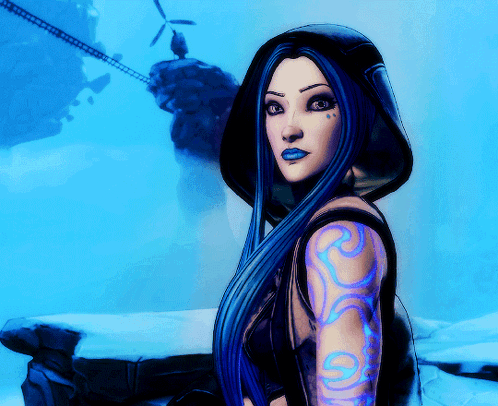 A Woman With Long Blue Hair Has A Tattoo On Her Arm With The Letter S On It GIF