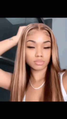 A Woman With Long Brown Hair And A White Tank Top Is Taking A Selfie With Her Eyes Closed . GIF