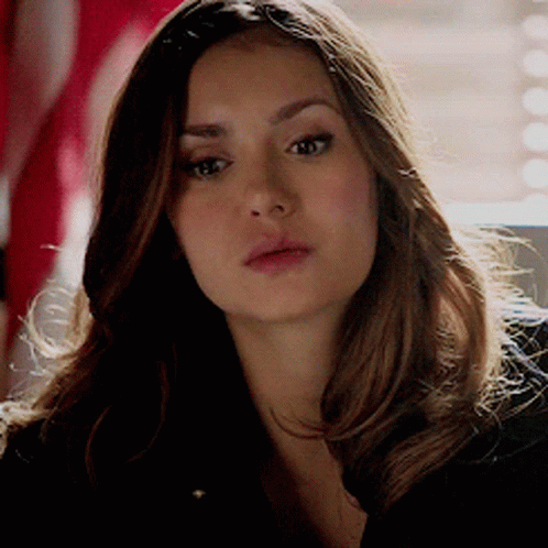A Woman With Long Brown Hair Is Looking At The Camera GIF